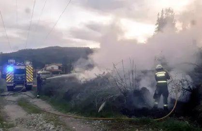 Los bomberos extinguen el fuego junto al tendido eléctrico en Somahoz.